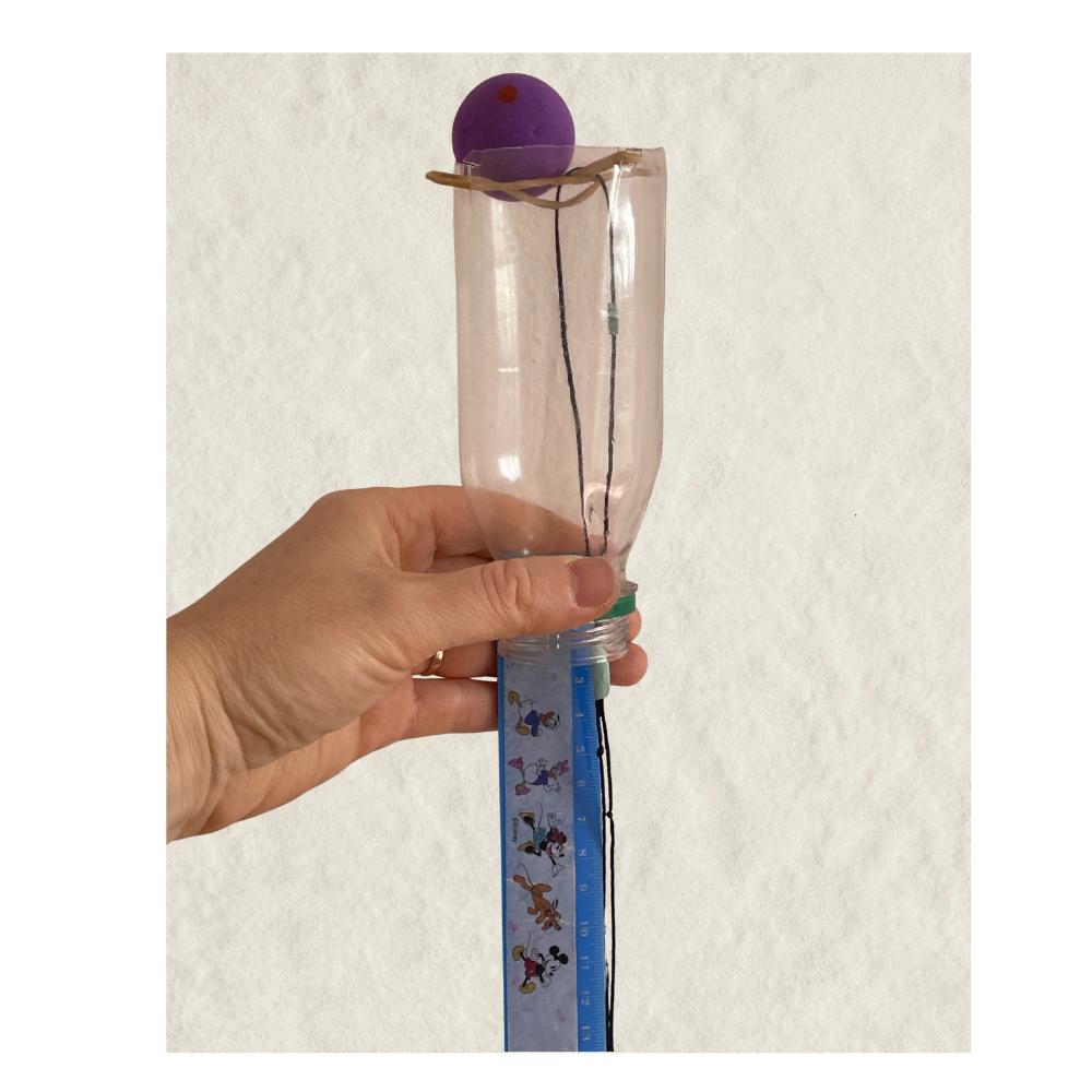 Close up of elastic bands stretched across the bottle opening with string looped over the intersection