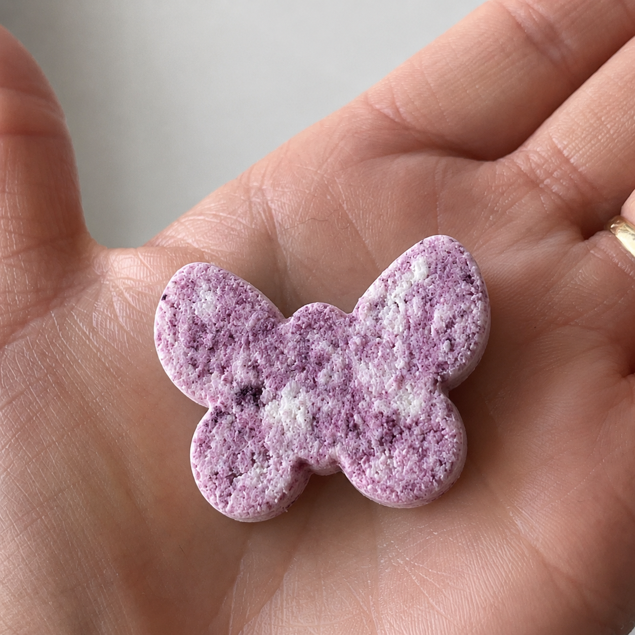 Girl holding homemade milk plastic butterfly — casein plastic chemistry experiment for kids